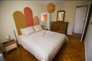 a white dog laying on a bed in a bedroom at Maisonbroca in Bourges