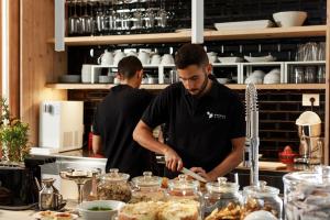 two men standing in a kitchen preparing food at Embrace Sicily Guest House in Noto