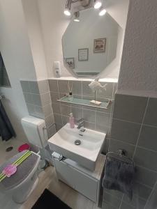 ein Badezimmer mit einem Waschbecken, einem WC und einem Spiegel in der Unterkunft Küstenliebe in Wilhelmshaven