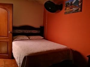 Bett in einem Zimmer mit orangefarbener Wand in der Unterkunft Hotel city of antigua s.a in Antigua Guatemala