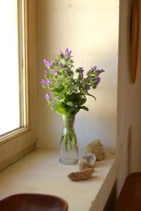 a vase filled with purple flowers sitting on a shelf at Casa Imayah in Noto