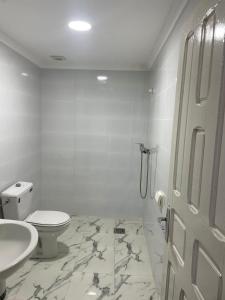 a white bathroom with a toilet and a sink at Chez azrou in Azrou