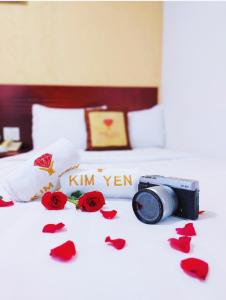ホーチミン・シティにあるキム イェン ホテルの赤いバラのペダルを持つベッドに座るカメラ