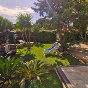césped con una silla azul y palmeras en Platamoon Garden - with enchanting garden, en Platamona