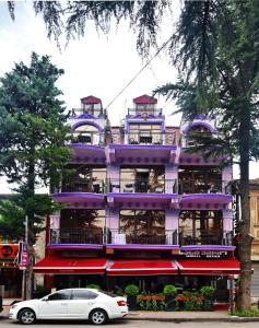 ein lila Gebäude mit einem davor geparkt in der Unterkunft Antika Hotel in Batumi