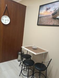 une table avec deux chaises et une horloge sur un mur dans l'établissement Apartamento Studio Central, à Navegantes