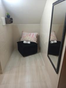 Cette petite chambre comprend un miroir et un canapé. dans l'établissement Apartamento Studio Central, à Navegantes