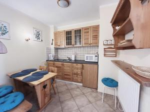a kitchen with wooden cabinets and a table and chairs at Apartament "Na fali" in Jarosławiec