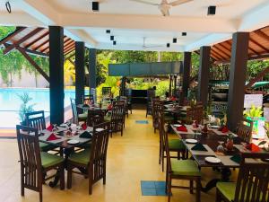 un restaurante con mesas y sillas y una piscina en THE Mangrove cave Hotel en Balapitiya