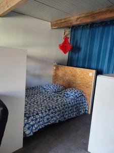 een kleine slaapkamer met een bed en een blauw gordijn bij tiny house in Les Sorinières