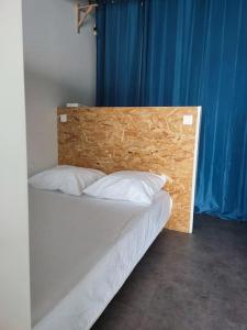 een bed met een houten hoofdeinde in een kamer bij tiny house in Les Sorinières