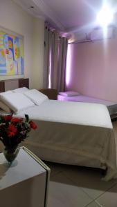 a bedroom with a large white bed with a table at Hotel Rio Branco in Jequié