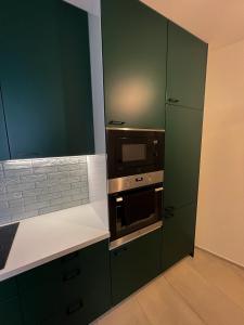 a kitchen with green cabinets and a microwave at Apartmán Melissa in Žilina