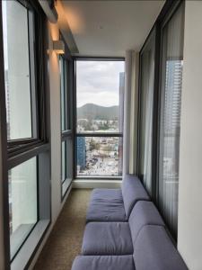 uma sala de estar com um sofá e janelas grandes em La Elbon stay in Haewoondae beach em Busan