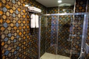uma casa de banho com um chuveiro e uma porta de vidro em ikarushotel em Aidim