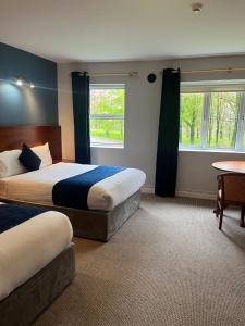 een slaapkamer met 2 bedden, een tafel en 2 ramen bij Fernhill Lodge Carrigaline in Cork