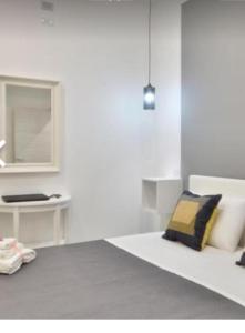 a white room with a bed and a mirror at B&B Iris in Santa Maria di Castellabate