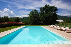 a swimming pool with lounge chairs and an umbrella at Locanda Fermento in Mochignano