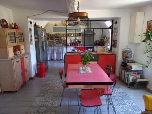 a kitchen with a red table and red chairs at La maison de vos vacances in Claret