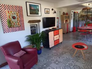 un soggiorno con una tv, una sedia e un tavolo di La maison de vos vacances a Claret