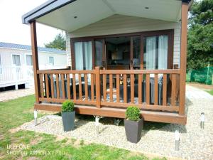 a screened in porch on a house with potted plants at Stag Lodge in Great Yarmouth