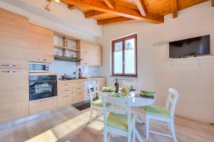 eine Küche mit einem Tisch und Stühlen sowie einem TV in der Unterkunft La Brezza Del Lago Maggiore with view - Happy Rentals in Laveno-Mombello