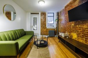 a living room with a green couch and a brick wall at Experience the Vibrant Energy of City Living in New York