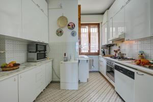 eine große Küche mit weißen Schränken und Geräten in der Unterkunft La Finestra Sul Lago - Happy Rentals in Stresa