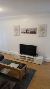 a living room with a flat screen tv on a white wall at Cosy 2 Bedroom Apartment in South West London in London