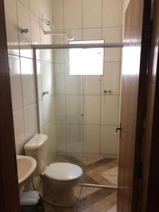 La salle de bains est pourvue de toilettes et d'une douche en verre. dans l'établissement Pousadaa São João 144, à Aparecida