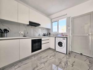 a kitchen with white cabinets and a washer and dryer at 2BD Garden Apartment in Paphos