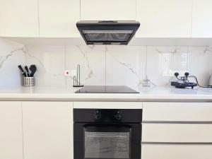 una cucina bianca con piano cottura e lavandino di 2BD Garden Apartment a Paphos