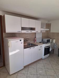 a kitchen with white cabinets and a sink and a refrigerator at Apartman Seka in Senj +11 photos