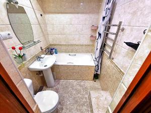 ein Badezimmer mit einem Waschbecken, einem WC und einem Spiegel in der Unterkunft City Center Apartment 1 in Taschkent