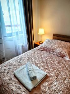a bed with a towel on it with a window at Hotel Blue Eye in Korçë