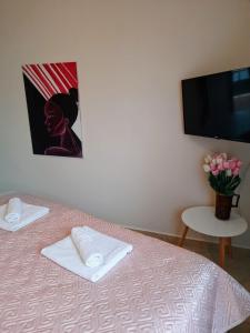a bedroom with a bed and a tv and a table with flowers at Hotel Blue Eye in Korçë
