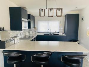 una cucina con armadi blu e un bancone con sgabelli di "The Penthouse Newquay" by Greenstay Serviced Accommodation - Stunning 3 Bed Apt With Parking & Sun Terrace - The Perfect Choice For Families, Small Groups & Business Travellers - Newly Refurbished - Close To Beaches, Shops & Restaurants a Newquay