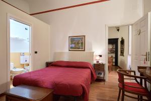 Affittacamere San Teodoro في ألبينغا: غرفة نوم بسرير وبطانية حمراء