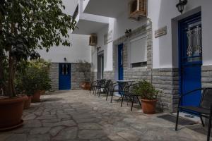 Soula Rooms Tinos في تينوس تاون: فناء مع كراسي وطاولة مع أبواب زرقاء