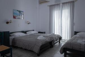 2 camas en una habitación con paredes blancas en Soula Rooms Tinos, en Tinos