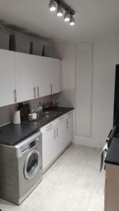 a kitchen with white cabinets and a washing machine at Cosy 2 Bedroom Apartment in South West London in London