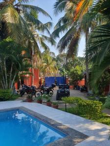 a group of motorcycles parked next to a house with palm trees at Bungalow 5 avec piscine à proximité de la plage in Nosy Be