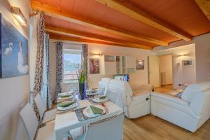 ein Wohnzimmer mit weißen Stühlen und einem Tisch in der Unterkunft Concordia Apartment Laveno - Happy Rentals in Laveno
