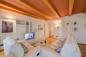 ein Wohnzimmer mit weißen Möbeln und einem Flachbild-TV in der Unterkunft Concordia Apartment Laveno - Happy Rentals in Laveno