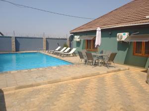 - une piscine avec des chaises et une table à côté d'une maison dans l'établissement ALIJAY APARTMENTS, à Mumbwa