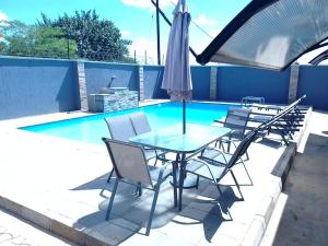 a table with chairs and an umbrella next to a swimming pool at ALIJAY APARTMENTS in Mumbwa