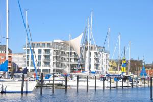 a group of boats docked in front of a building at Apartmenthaus Hafenspitze Ap 28, Blickrichtung InnenstadtBinnenhafen - a72338 in Eckernförde
