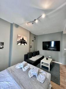 a bedroom with a bed and a couch and a flat screen tv at Light Budget Studio Apartment on Edgware Road, Central London in London