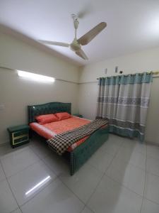 a bedroom with a green bed and a ceiling fan at Modern Luxury Guest Apartment With All Facilities in Karachi