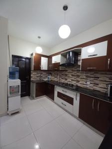 a large kitchen with brown cabinets and white tiles at Modern Luxury Guest Apartment With All Facilities in Karachi